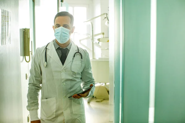 Siyah Saçlı Beyaz Önlüklü Cerrahi Maskeli Bir Doktor Elinde Tabletle — Stok fotoğraf