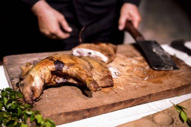 Ahşap kesme tahtasının üzerinde pişmiş taze parçalara ayrılmış süt domuzu.