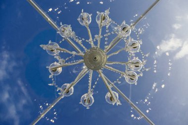 Mavi gökyüzünde asılı beyaz tavan avizesi. 