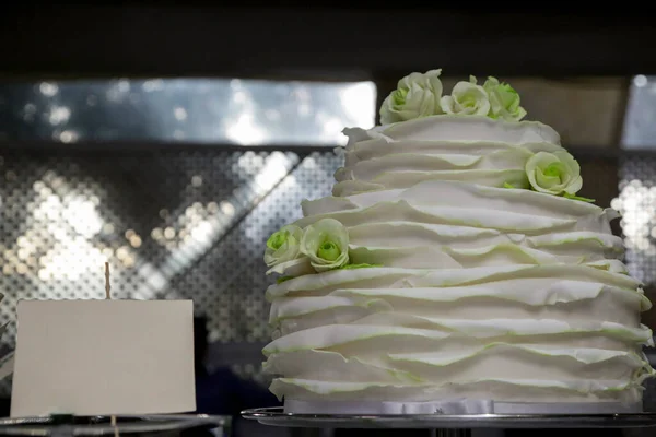 a wedding cake with a beautiful white rose on the background of a white table