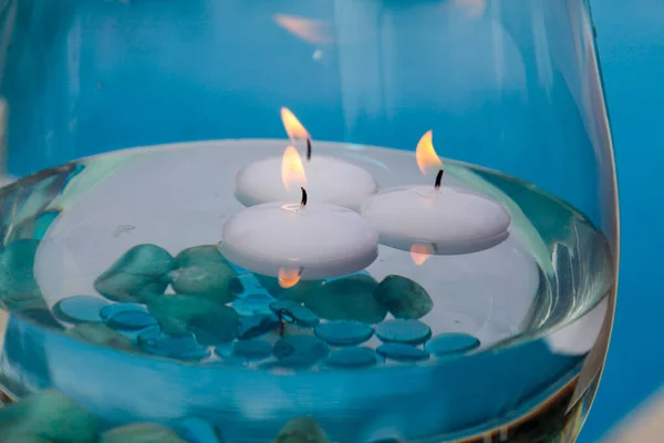 玻璃与燃烧的蜡烛和蓝色的水 — 图库照片