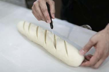 Şef mutfak masasında hamur yapıyor. 