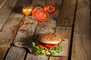 Hamburger, sığır eti, domates ve peynir ahşap arka planda.