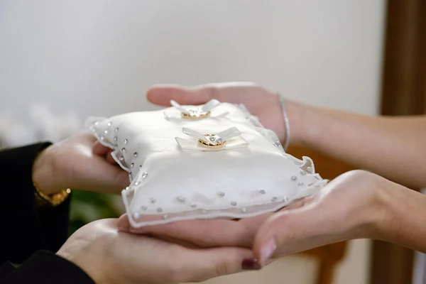 stock image hands holding wedding rings on a pillow 