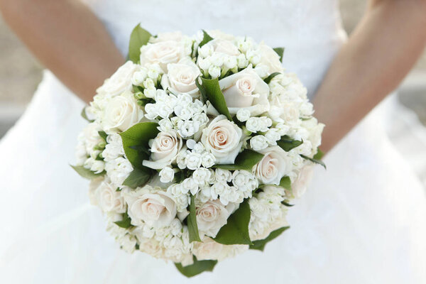 beautiful bride holding wedding bouquet of white roses 