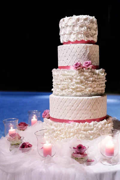 white cake with pink candles on a blue background with flowers and candles.