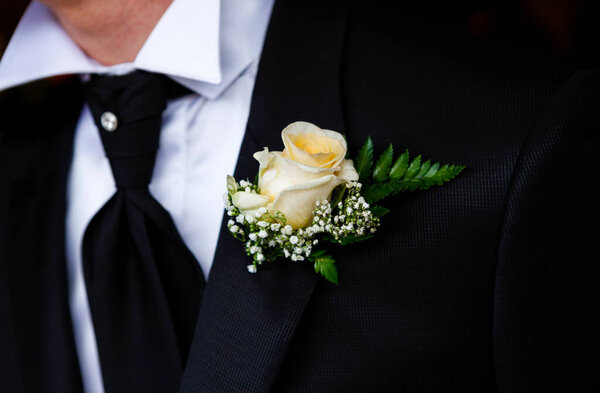close up of a groom in a suit with a white bow 