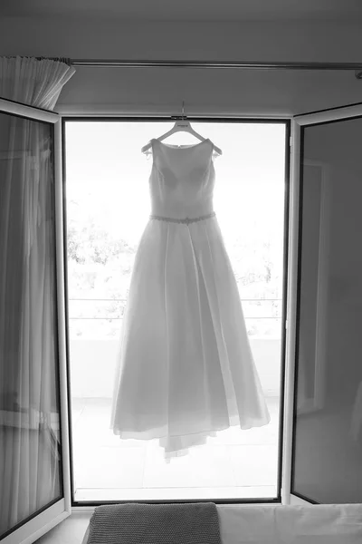 stock image white dress hanging on the hanger on the window of a hotel 