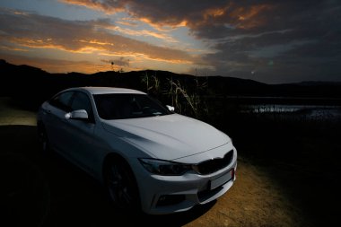 Gün batımında güzel bir gökyüzünün arka planında bir araba 