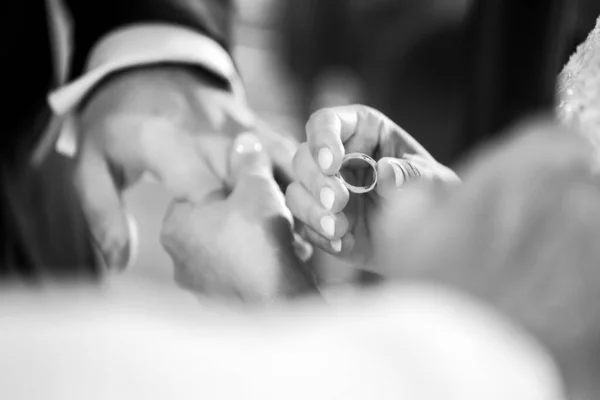 新郎の指に結婚指輪をしている花嫁のクローズアップ 白黒写真です — ストック写真