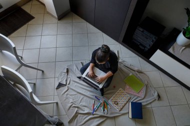 Evde ev ödevi yapan genç bir kadın.