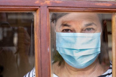 Evinde maske takan yaşlı bir kadın.