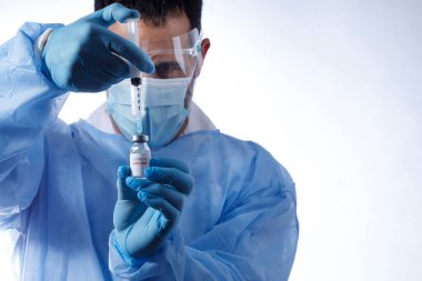 Cerrahi maskeli ve lateks eldivenli bir doktor beyaz arka planda izole edilmiş cam şişeden anti-covid aşıyı aldı.