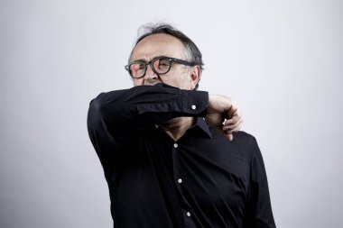 Gözlüklü olgun bir adam, elleri arkada.