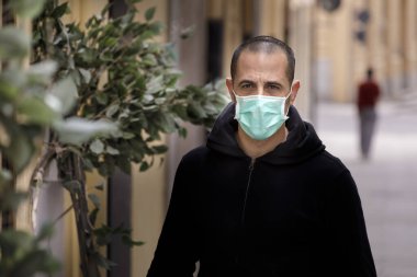 Terkedilmiş şehirde maskeli ve siyah kazaklı bir adam dolaşıyor.
