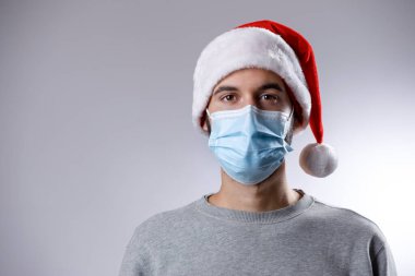 Tıbbi maskeli, noel şapkalı bir adam. yüksek kaliteli fotoğraf