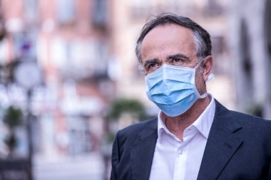 Şehir bağlamında koruyucu maskeli takım elbiseli bir adam.