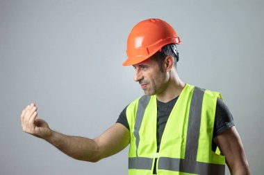 Koyu renk saçlı, kasklı, sarı yelekli, açık arkaplanda izole edilmiş bir portre.