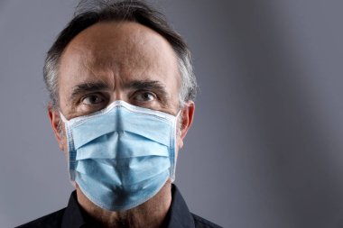Arka planda cerrahi maske takan bir adamın portresi.