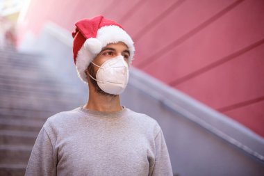 Koruyucu şapkalı ve maskeli genç adam alt geçide iniyor.