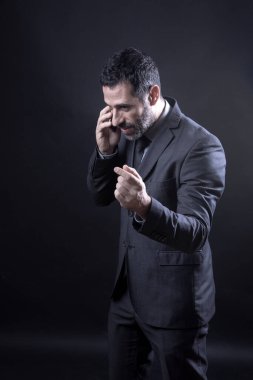Seçkin takım elbiseli yönetici telefonda siyah arka planda izole bir şekilde konuşuyor.