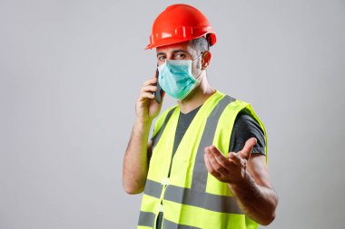 Koruyucu kasklı, maskeli ve solungaçlı işçiler telefonda konuşuyor.