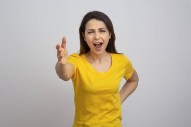 Sarı gömlekli esmer kız kızgın, beyaz arka planda soyutlanmış.