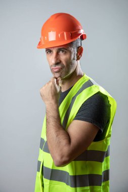 Koyu renk saçlı, kasklı, sarı yelekli, açık arkaplanda izole edilmiş bir portre.