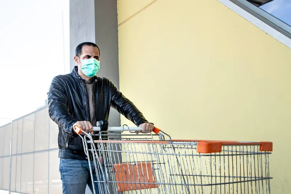 身穿休闲装 身穿皮夹克 戴着防护面罩的男人 开着购物车 与黄色的墙壁隔离 在超市购物 — 图库照片