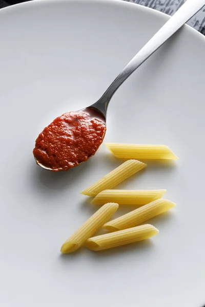 Ongekookte Penne Pasta Met Een Lepel Tomatenpuree Een Wit Bord — Stockfoto