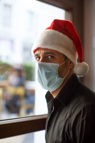 Noel Baba Şapkalı Cerrahi Maskeli Bir Adam Pencereden Evin Dışında — Stok fotoğraf