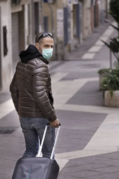 頭にはジャケットとサングラスをかけた暗い男です手術用の保護マスクをしています彼はトロリーシティの周りにいます — ストック写真
