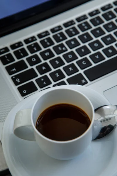 detail of cup with coffee on top of a laptop