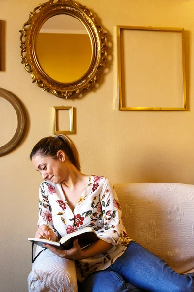 一个小女孩坐在一个房间里 一边喝咖啡 一边看书 一边看相机 — 图库照片