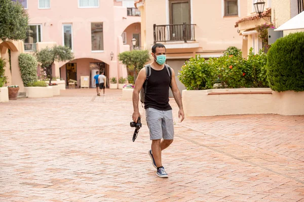 身穿夏装和背包的黑头发男子带着护肤面罩在度假村附近散步 — 图库照片