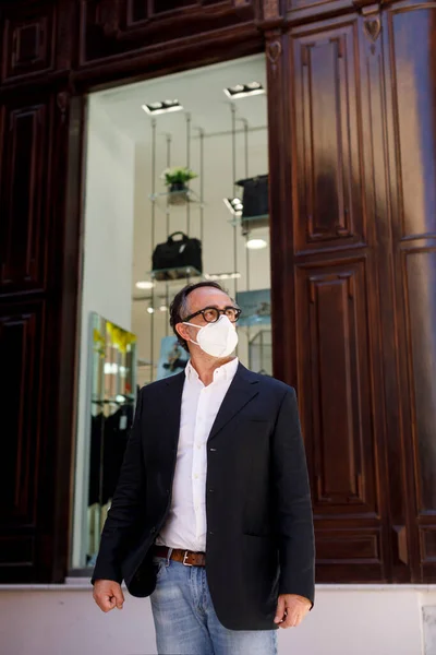 在市中心的街道上 一个戴着黑色眼镜 戴着Kn95型面罩的男人站在一家商店前面 — 图库照片
