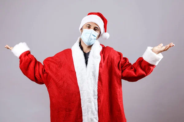 带着外科面具的圣诞老人把他的胳膊举到天上 被白色的背景隔开了 — 图库照片