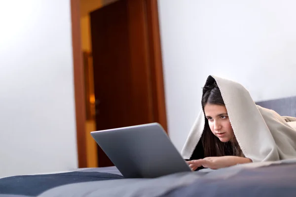 一个黑头发 毛毯的小女孩 把房间里的电脑当作头巾 头上蒙着毛毯 — 图库照片