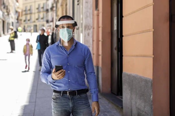 在城市里 戴着便装面具的男人一边打电话一边保护自己 — 图库照片