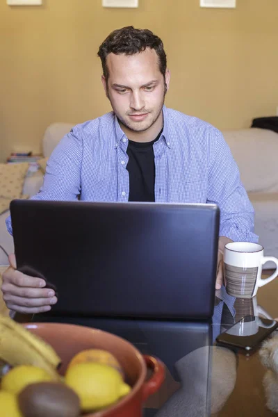 ノートパソコンとコーヒーカップを持つ若い男 — ストック写真