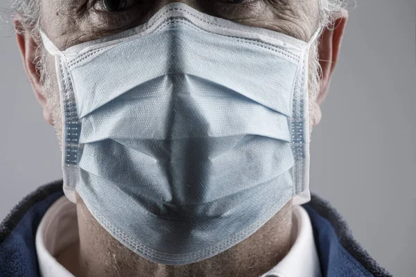 Portrait of man wearing a surgical mask isolated on background