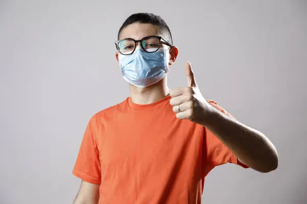 의료용 마스크를 배경에 엄지를 젊은이입니다 코로나 바이러스 — 스톡 사진