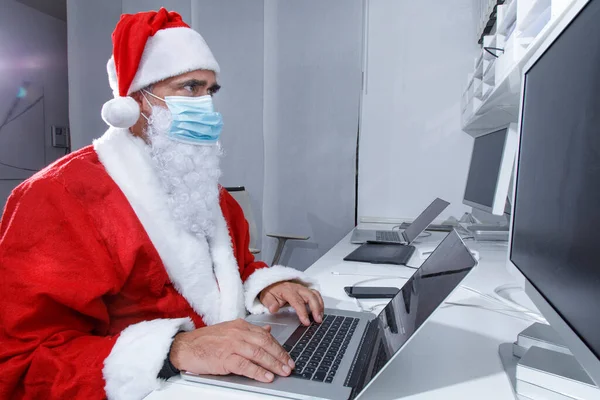 Santa Claus Con Máscara Quirúrgica Sentado Oficina Utiliza Ordenador Para —  Fotos de Stock