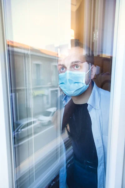 コロナウイルスのパンデミックの際に家のドアに立っている医療用保護マスクと手袋を身に着けている若者は — ストック写真