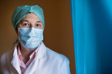 Hastanede tıbbi maske takan olgun bir kadının portresi.