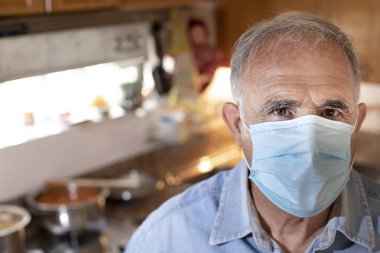 Kamera karşısında maske takan yaşlı bir adamın portresi. ev karantina konsepti
