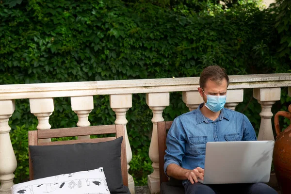 Bahçesinde Oturan Dizüstü Bilgisayarı Maskesi Olan Bir Adam — Stok fotoğraf