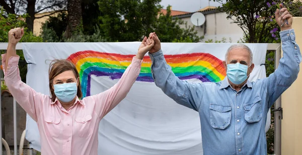 Älteres Paar Mit Operationsmaske Lässig Gekleidet Vor Einer Regenbogenzeichnung Einem — Stockfoto