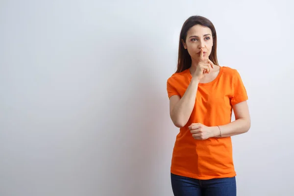 Bruna Ragazza Con Camicia Arancione Chiama Silenzio Con Indice Isolato — Foto Stock