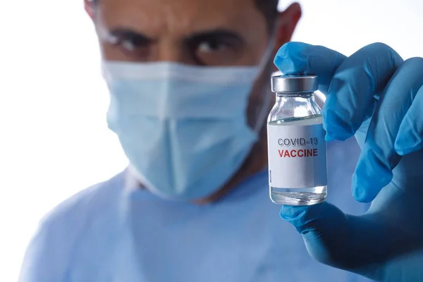 外科用マスク プロテクター ラテックス手袋を持つ男は 白い背景に隔離された抗Covidワクチンの瓶を保持しています — ストック写真